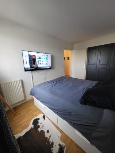 une chambre avec un lit et une télévision à écran plat dans l'établissement appartement lumineux à 10mn de Paris, à Romainville