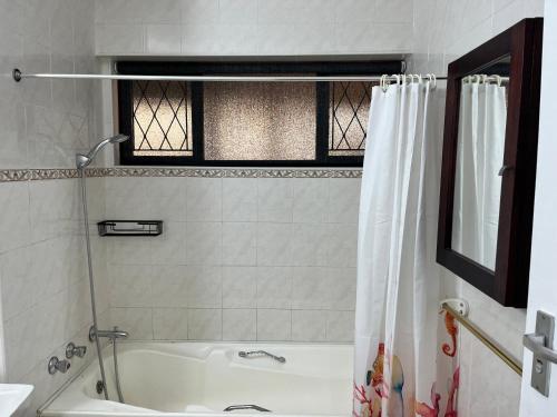 a bathroom with a tub and a shower curtain at Stella Maris Flat 93 Amanzimtoti in Amanzimtoti