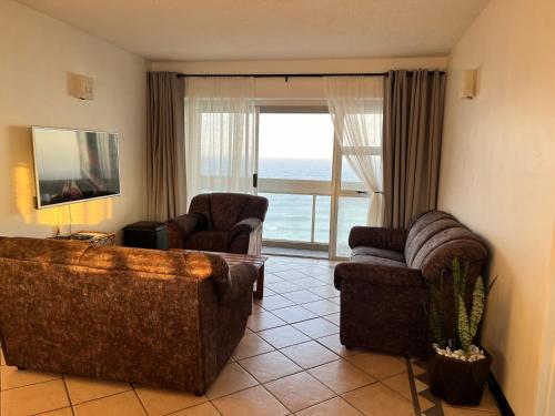 a living room with a couch and two chairs and a window at Stella Maris Flat 93 Amanzimtoti in Amanzimtoti