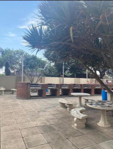 a group of picnic tables and a tree at Stella Maris Flat 93 Amanzimtoti in Amanzimtoti
