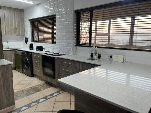 a large kitchen with white counter tops and appliances at Stella Maris Flat 93 Amanzimtoti in Amanzimtoti
