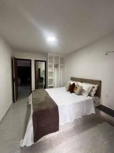 um quarto com uma cama grande com lençóis brancos e almofadas em Bangalô no condomínio Victory em Lucena-PB em Lucena