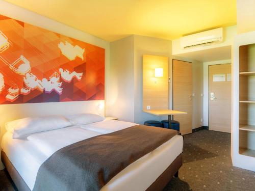 シュトゥットガルトにあるB&B Hotel Stuttgart-Bad Cannstattのベッドルーム1室(壁に絵画が描かれたベッド1台付)
