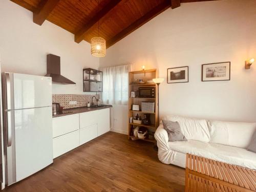 uma cozinha e sala de estar com um sofá e um frigorífico em Casita independiente con jardin em Cercedilla