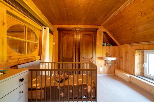 łóżeczko dziecięce w pokoju z drewnianym sufitem w obiekcie La ferme du Ravet - Gîte aux Lacs de l'Eau d'Heure w mieście Froid-Chapelle