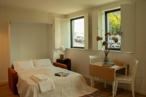 a bedroom with a bed and a table and a window at Casa da Carvoaria in Vila Real