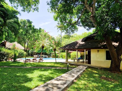 a resort with a pool and a building with a tree at Giant House Malindi in Malindi