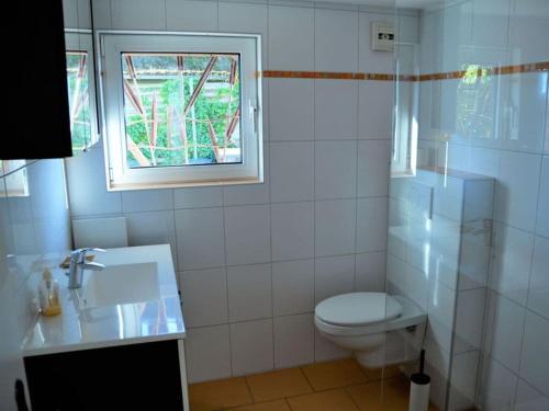 La salle de bains blanche est pourvue de toilettes et d'une fenêtre. dans l'établissement Holiday house house by the lake, à Krakow am See