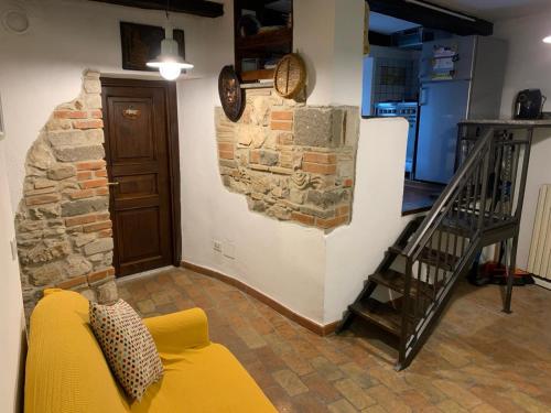 a living room with a yellow couch and a stone wall at Il Carpino Historic Luxury Home - dimora con sauna in Carpineto Romano