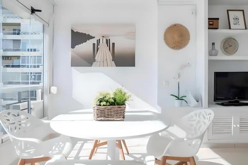 トレモリノスにあるPrecioso apartamento reformado con vistas directas al marの白いダイニングルーム(白いテーブルと椅子付)