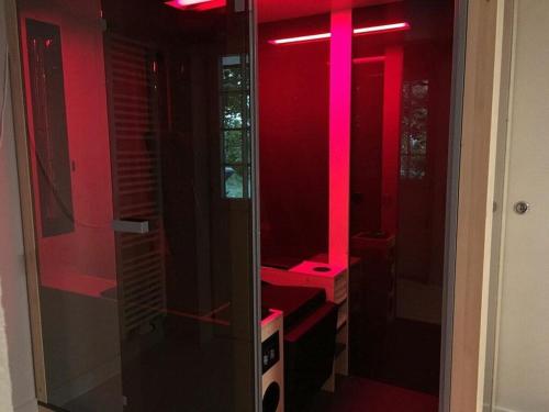 a red bathroom with a glass shower with pink lights at Apartment Mini Suite in Höchenschwand