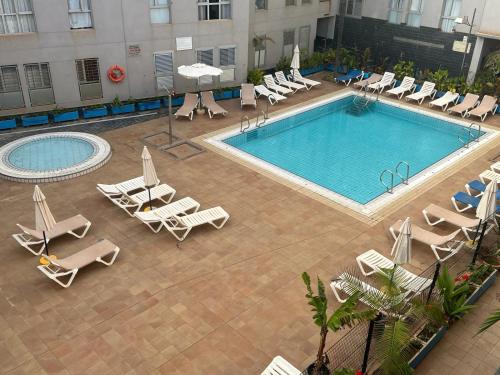 an overhead view of a pool with chaise lounge chairs at Acogedor apartamento con piscina yedae in Gáldar