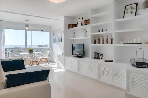 トレモリノスにあるPrecioso apartamento reformado con vistas directas al marの白いリビングルーム(ソファ、テーブル付)