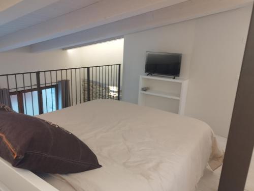 a bedroom with a white bed with a television at Villetta Vittoria Country House. La depandance in Pennabilli