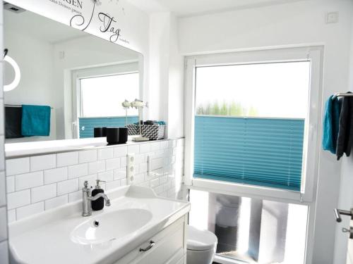 ein weißes Badezimmer mit einem Waschbecken und einem Spiegel in der Unterkunft Holiday apartment Elbe 