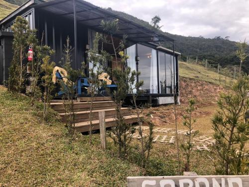 a black house on a hill with two people in front of it at Cabana Fortaleza - Pousada Colina dos Ventos in Urubici