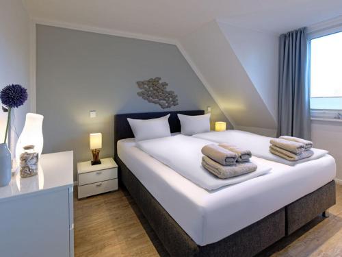 een slaapkamer met een groot wit bed en handdoeken bij Holiday apartment Langeoogtraum in Langeoog