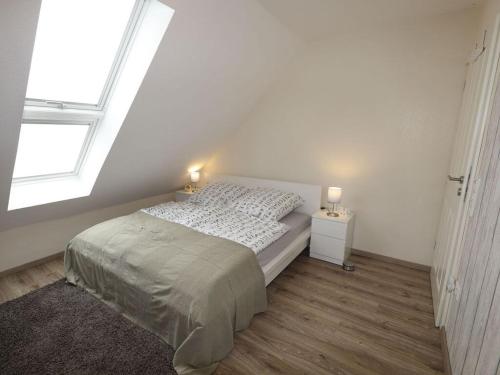 a white bedroom with a bed and a window at Holiday apartment Ponywiese in Ihlow