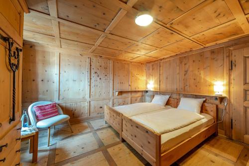 a bedroom with a bed and a chair in a room at Weisses Kreuz - Crusch Alva in Samedan