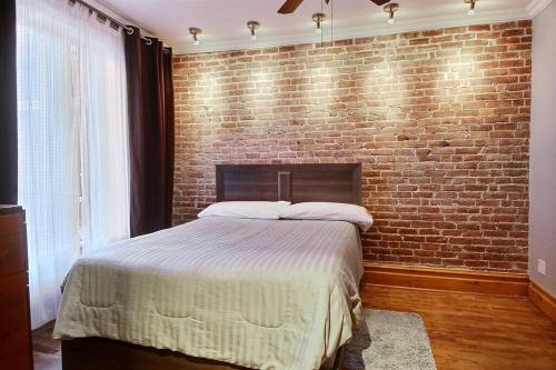 a bedroom with a brick wall and a bed at Irresistible 2 bedroom condo, excellent location in Montréal