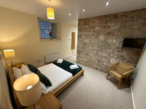 sypialnia z łóżkiem i kamienną ścianą w obiekcie Edmonstone Suite Old Town w Edynburgu