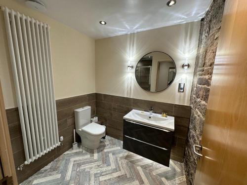W łazience znajduje się toaleta, umywalka i lustro. w obiekcie Edmonstone Suite Old Town w Edynburgu
