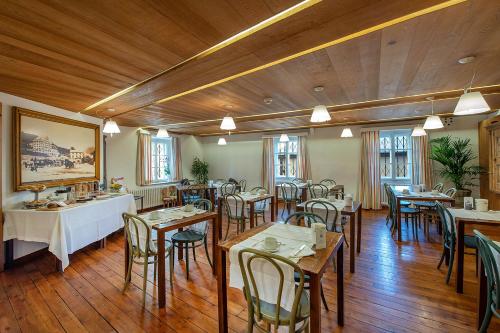 un ristorante con pavimenti e tavoli in legno e sedie di Weisses Kreuz - Crusch Alva a Samedan