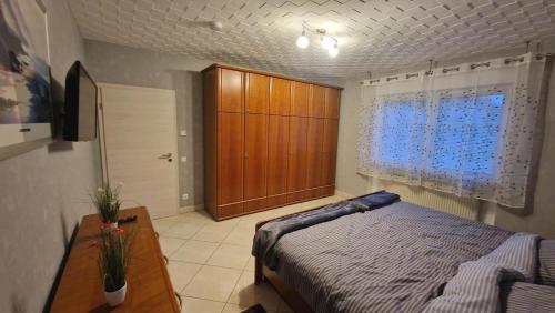 a bedroom with a bed and a wooden cabinet at Ferienhaus Guldner mit Terrasse, Garten und Sauna in Überherrn