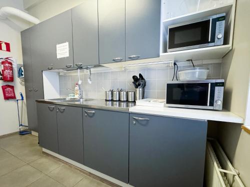 uma cozinha com armários cinzentos e um micro-ondas em Hostel Hermanni em Kuopio
