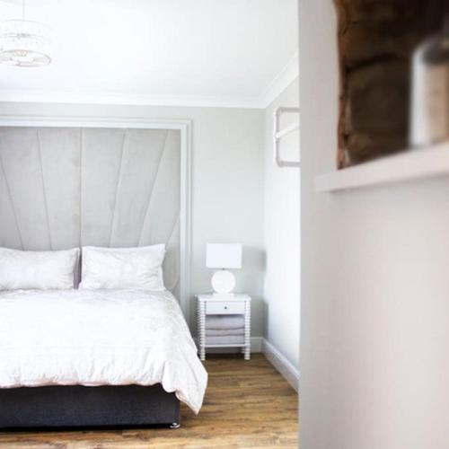a bedroom with a white bed and a night stand at Lilydale Retreat in Lanchester