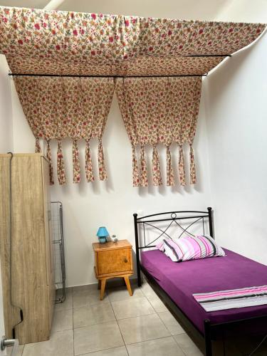 una camera da letto con letto con lenzuola e tende viola di Lemonia a Megara
