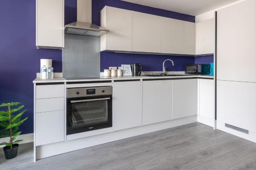 a kitchen with white cabinets and a stove at Hemel Apartments - Lilac Luxe in Hemel Hempstead