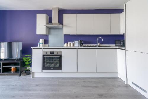 a kitchen with white appliances and purple walls at Hemel Apartments - Lilac Luxe in Hemel Hempstead
