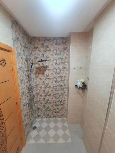 a bathroom with a shower with a tiled wall at Appartement Maghrib Jadid in Larache