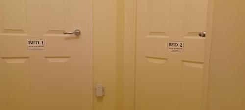 two white doors with signs on them in a bathroom at Aylesbury Lovely Double and Single Bedroom with Guest only Bathroom in Buckinghamshire