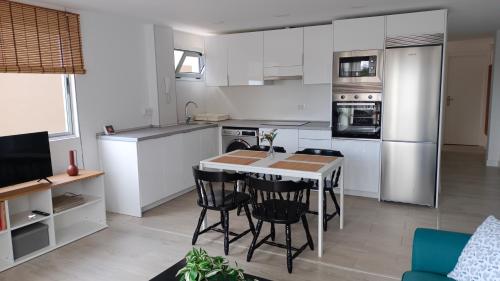 une cuisine avec des armoires blanches et une table et des chaises dans l'établissement Apartamento Tajinaste con vistas al mar y la montaña y wifi gratis, à Los Realejos