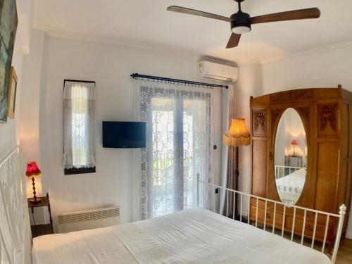 a bedroom with a bed with a ceiling fan and a mirror at "Ariane" - Afytos village with sea view in Afitos