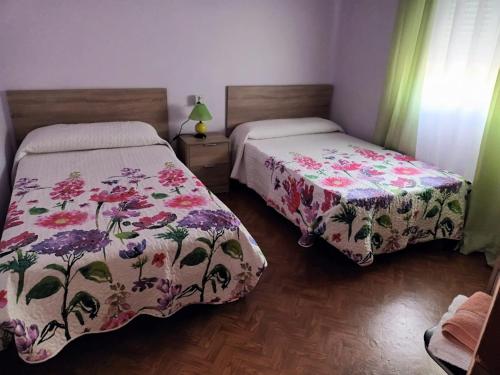 1 dormitorio con 2 camas con colchas de flores en Pensión O Regato en Redondela