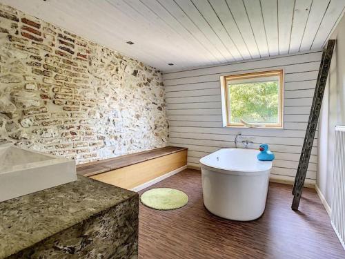 a bathroom with a tub and a stone wall at Clos des Rogations in Saint-Hubert