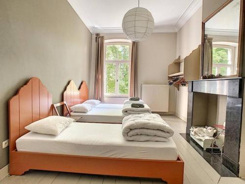 dwa łóżka w pokoju z kominkiem w obiekcie Clos des Rogations w mieście Saint-Hubert
