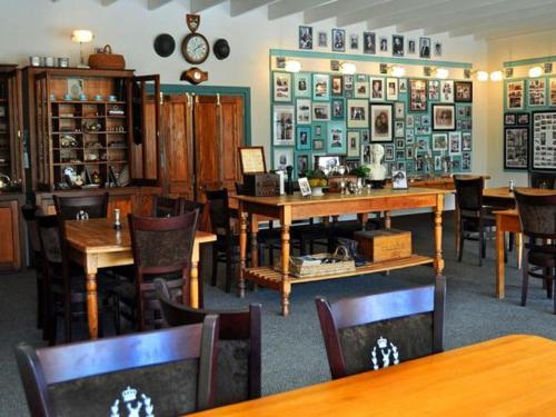 a dining room with tables and chairs and a room with clocks at Cleopatra Mountain Farmhouse in Fort Nottingham