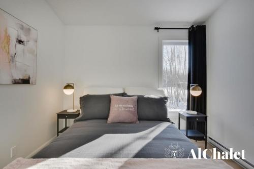 a bedroom with a bed and two lamps and a window at Achille - Wooded with spa and sauna in Pont-Rouge