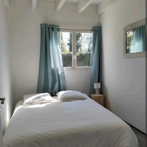 - une chambre avec un grand lit blanc et des rideaux bleus dans l'établissement Villa Marylou, à Seignosse