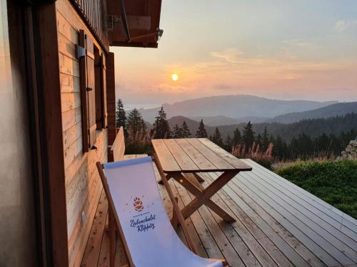 a picnic table and a chair on a deck with the sunset at Zirbenchalet Klippitz - Erholung mit Zirbenkraft in Bad Sankt Leonhard im Lavanttal