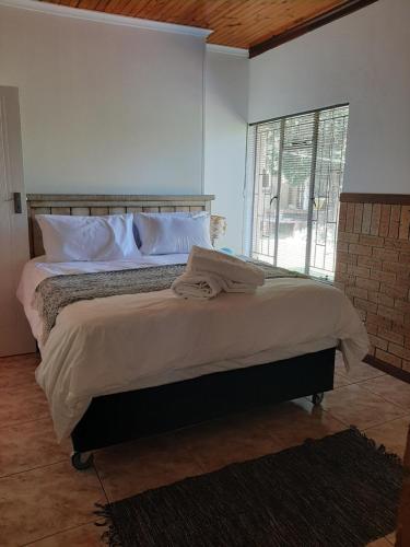 a bedroom with a large bed with white sheets and a window at The Cottage at 19 in Kempton Park