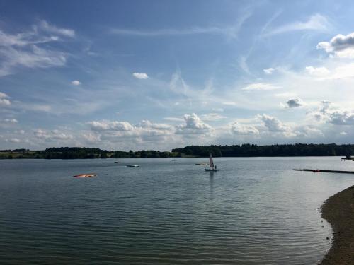 a large lake with a sail boat in the water at La ferme du Ravet - Gîtes aux Lacs de l'Eau d'Heure in Froid-Chapelle