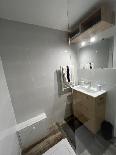 une salle de bain blanche avec un lavabo et un miroir dans l'établissement Jolie maisonnette rénovée, à Saint-Cyprien