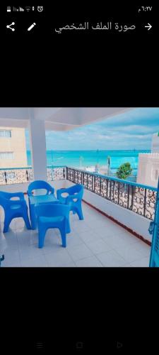 un grupo de bancos azules sentados en un balcón con vistas a la playa en Queen Home Hotel en Marsa Matruh