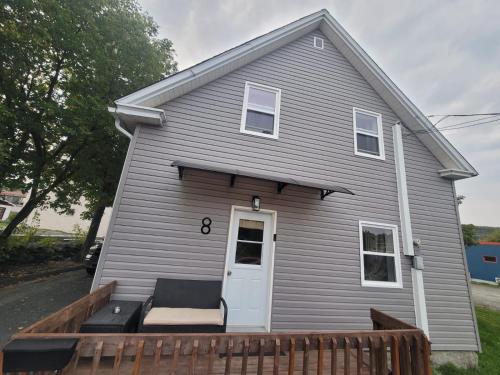 a gray house with a porch and a white door at Warm cozy 1 bdrm close to Hwy in Edmundston