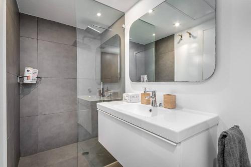 uma casa de banho branca com um lavatório e um espelho em « The Sea » Penthouse with sea view by Host Eretz em Tel Aviv